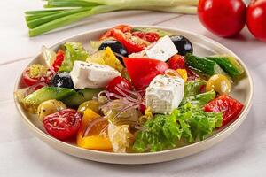 A plate of salad with tomatoes, cucumbers, onions, and feta cheese photo