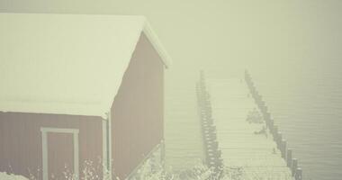 CGI Winter morning with a red cabin and a snowy dock in fog video