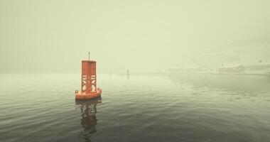 CGI Buoy floats in foggy waters near coastal town as mist envelops landscape video