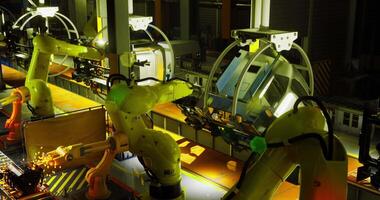 CGI Industrial robots at night working on assembly line in a manufacturing facility video