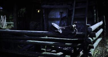 CGI Saddle resting on wooden fence near rustic barn at dusk in rural setting video