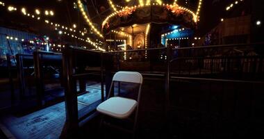 CGI Empty chair beside a colorful carousel during a nighttime fair atmosphere video