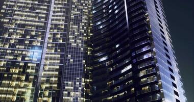 CGI Tall modern skyscraper illuminated at night in an urban environment video