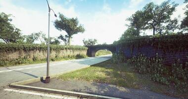 CGI Empty country road passing under a stone bridge surrounded by greenery video