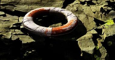 CGI Lifebuoy resting on rocky shore near water during bright daylight video