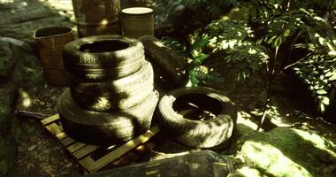 CGI Old tires and barrels are stacked in a forested area near a rocky path video