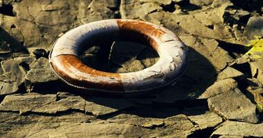 CGI Lifebuoy resting on rocky shoreline with sunlight illuminating the surface video