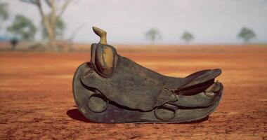 CGI Old saddle resting on dry ground under a clear sky in remote area video