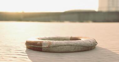 CGI Lifebuoy resting on sandy surface under warm sunset glow near water video