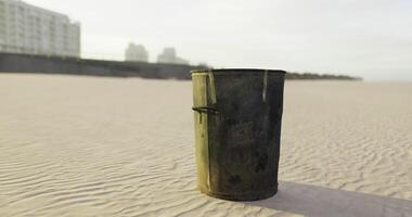 CGI Trash bin standing alone on a sandy beach by a cityscape at dusk video