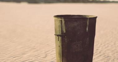 CGI A rusty trash bin stands on a sandy beach as waves gently lap the shore video