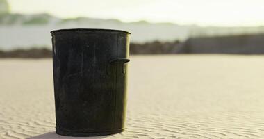 CGI Black trash bin on sandy beach with ocean background during sunset video