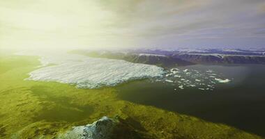 CGI Glacier melting into ocean at dawn with bright sunlight illuminating landscape video