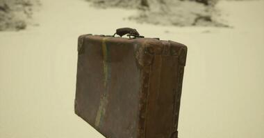 CGI Old leather suitcase resting on sandy surface in deserted area during daylight video