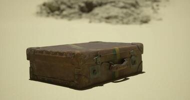 CGI Old suitcase resting in sand with rocky background in desert landscape video