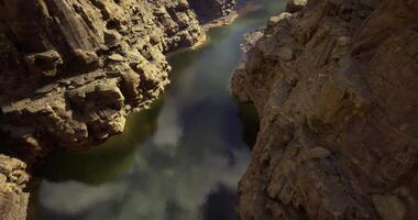 CGI River flows through rocky canyon under blue sky with scattered clouds video