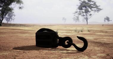 CGI Rusty hook rests on cracked earth in deserted landscape under cloudy sky video