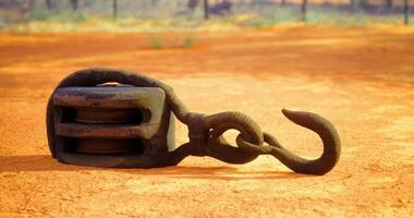 CGI Heavy metal hook and pulley resting on dry earth in open landscape video