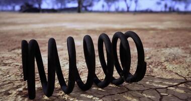 CGI Coiled wire lays on cracked earth under a cloudy sky in a deserted landscape video