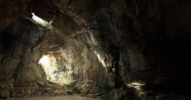 CGI A cavern showcases rugged rock formations with light streaming through openings video