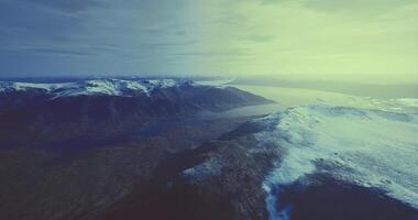 CGI Breathtaking aerial view of snow capped mountains and glacial lakes at dawn video