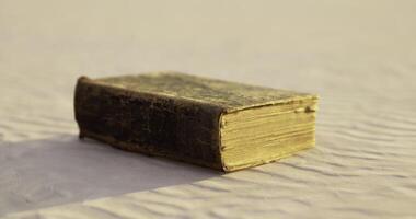 CGI Ancient book resting on sand with textured surface illuminated by sunlight video