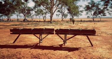 CGI Empty wooden troughs sit under a clear sky in an arid landscape video