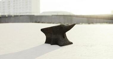 CGI Anvil resting on sandy surface in bright sunlight near industrial area video