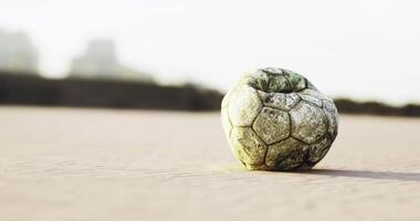 CGI Old soccer ball rests on sandy beach at sunset with soft light surrounding video