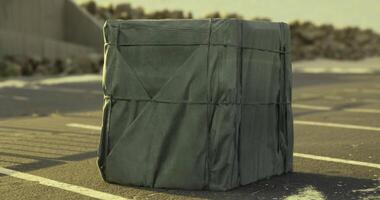 CGI Wrapped rectangular object sits on asphalt surface at urban location video