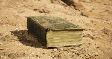 CGI Ancient book resting on dry soil in an outdoor setting during daylight video