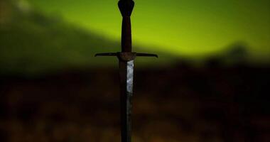 CGI Sword embedded in rock under a glowing green sky during nighttime video