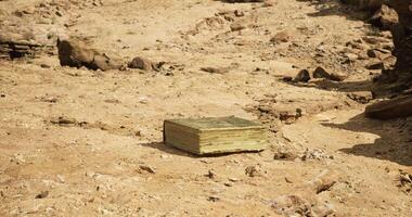 CGI Ancient book resting on dry desert ground surrounded by rocks and sand video
