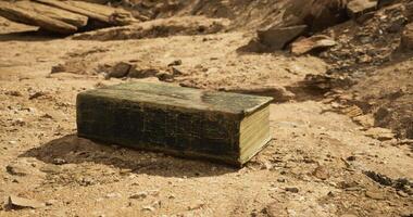 CGI Old book resting on dry desert ground with rocks and sand in background video