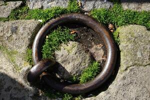 Rusty iron ring on stone with moss, close up of weathered metal and stonework photo