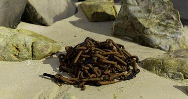 CGI Pile of rusty chains resting on sandy ground surrounded by stones video