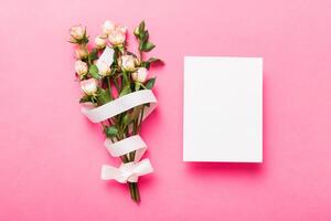 Greeting holiday card mockup with fresh roses on colored table background, mock up with copy space photo