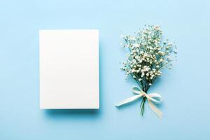 Wedding mockup with white paper list and flowers gypsophila on colored table top view flat lay. Blank greeting cards and envelopes. Beautiful pattern. photo