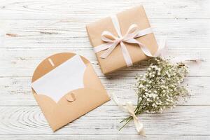 Wedding mockup white paper list and flowers gypsophila on colored table top view flat lay. Blank greeting cards and envelopes. Beautiful pattern. photo