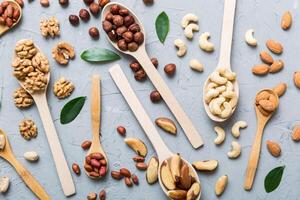 mixed nuts white wooden spoon. Mix various nuts on colored background. pistachios, cashews, walnuts, peanuts and brazil nuts photo