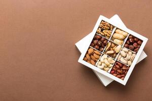 Various varieties nuts lying in paper box on table background. Top view. Healthy food. Close up, copy space, top view, flat lay. Walnut, pistachios, almonds, hazelnuts and cashews photo