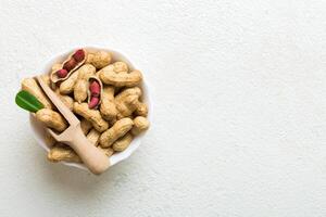 Fresh healthy peanuts in bowl on colored table background. Top view Healthy eating bertholletia concept photo