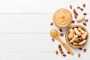 Bowl of peanut butter and peanuts on table background. top view Creamy peanut pasta photo