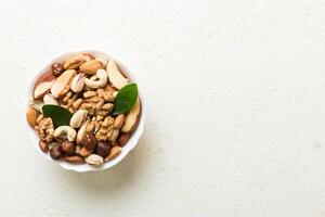 mixed nuts in bowl. Mix of various nuts on colored background. pistachios, cashews, walnuts, peanuts and brazil nuts photo