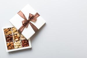 Various varieties nuts lying in paper box on table background. Top view. Healthy food. Close up, copy space, top view, flat lay. Walnut, pistachios, hazelnuts and cashews photo