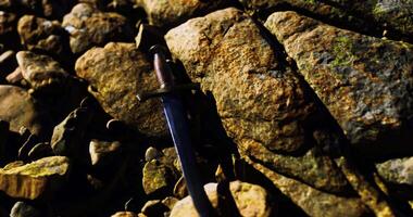 CGI Sword resting on rocky shore with sunlight reflecting off the stones video