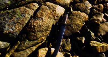 CGI Old sword resting on rugged rocks near a riverbank during golden hour video