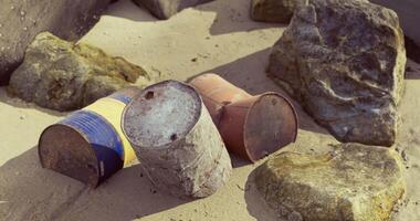 CGI Weathered barrels on sandy beach near rocky formations during daylight video