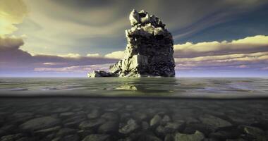 CGI Lonely rock formation rising above calm water under dramatic cloudy sky video