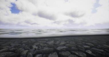 CGI Calm water reflecting clouds above with submerged rocks below the surface video
